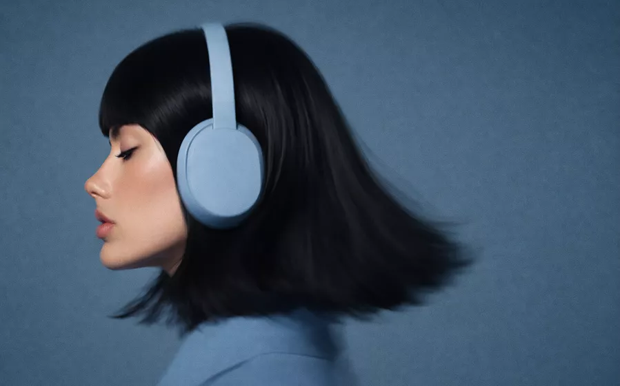 A woman with blue headphones, her head turned to the side, appears focused and engaged in listening